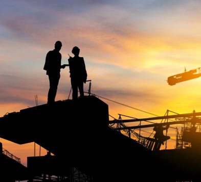 Silhouette of Engineer and worker checking project at building site background, construction site at sunset in evening time.